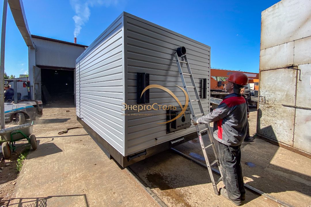 Монтажник проводит визуальную проверку корпуса и дымового патрубка безнакипного котла КВр на заводской площадке «ЭнергоСталь».