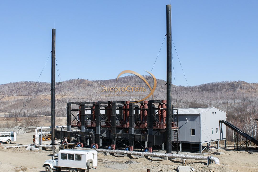 Главный фасад котельной с площадкой обслуживания и группой циклонов. Газоходы сводят дымовые газы от каждого КВм-2,5МВт, обеспечивая устойчивую тягу и очистку перед трубой.