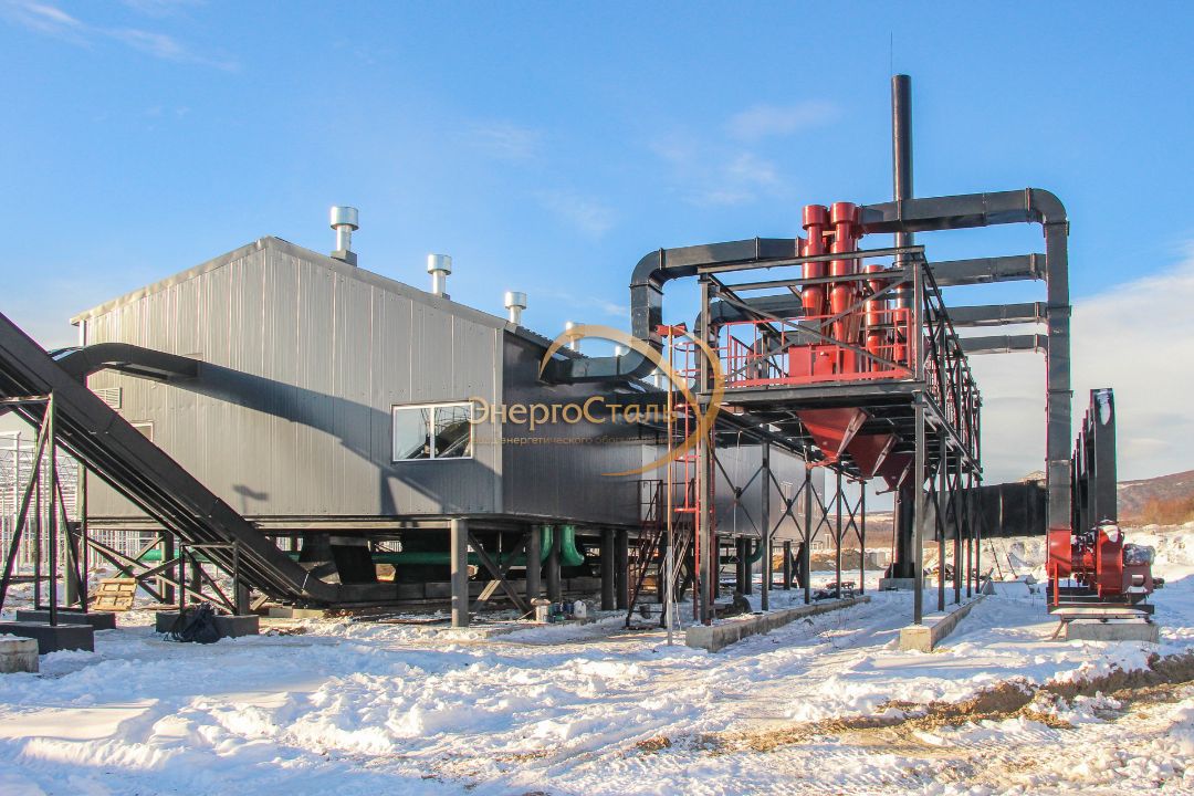 Главный фасад котельной с площадкой обслуживания и группой циклонов. Газоходы сводят дымовые газы от каждого КВм-2,5МВт, обеспечивая устойчивую тягу и очистку перед трубой.