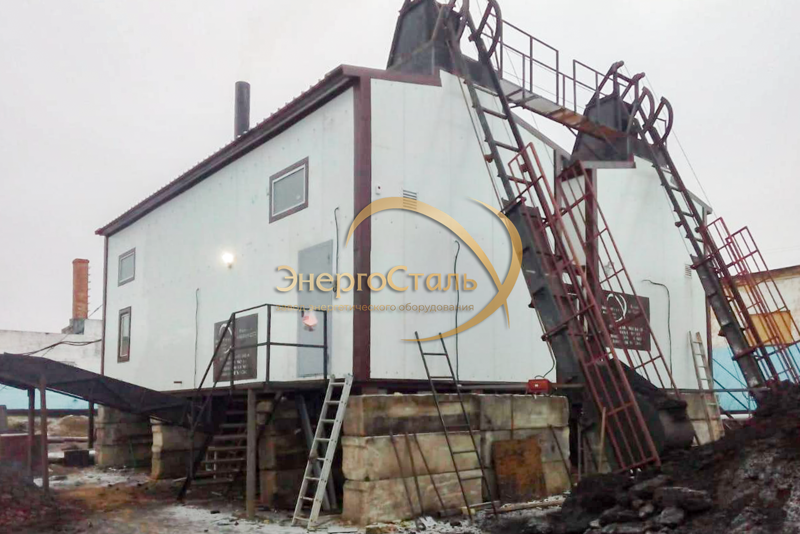 Главный фасад котельной со скиповыми шахтами. Здания собраны в контейнерном исполнении, установлены на бетонном основании с утеплённым перекрытием. На снимке — подача топлива к верхним загрузочным люкам.