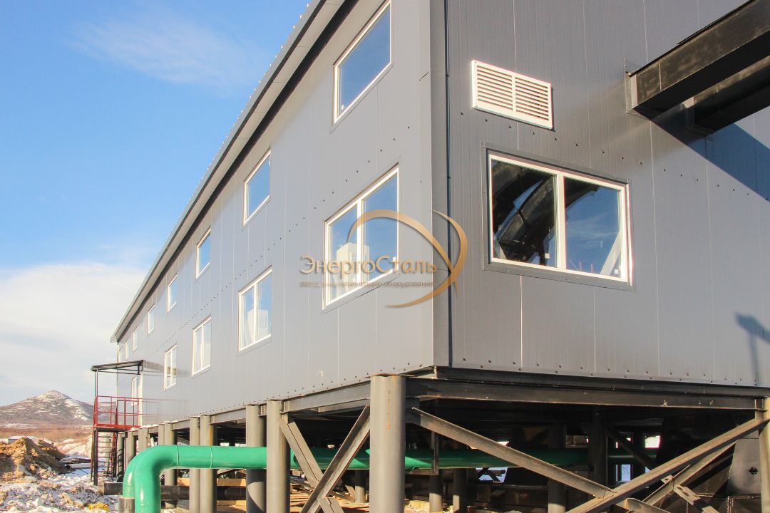 Двухпролётный тёплый блок МКУ-10МВт на металлических опорах. Под корпусом — магистральные коллекторы и обратка; высота позволяет безопасно вести эксплуатацию при снеговых заносах и промерзании грунта.